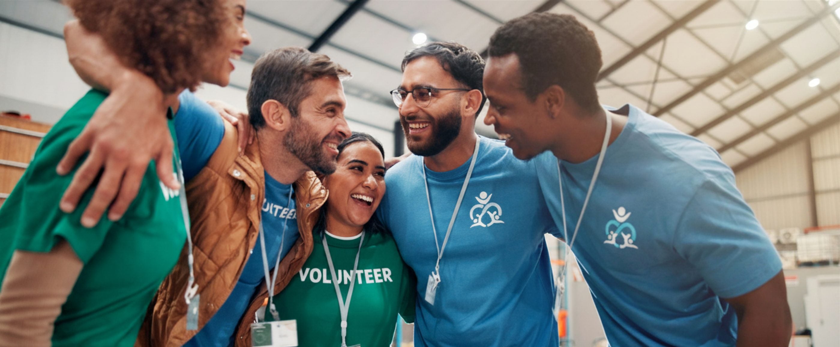 Team in matching branded blue and green custom t-shirts with printed logos, arms around each other