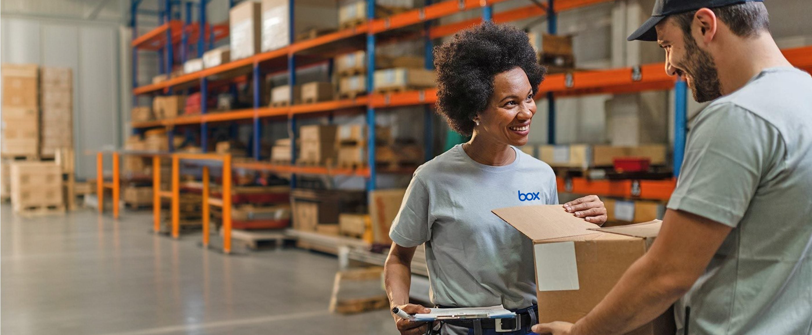 Warehouse staff in branded custom t-shirts handing over a packed order box for despatch